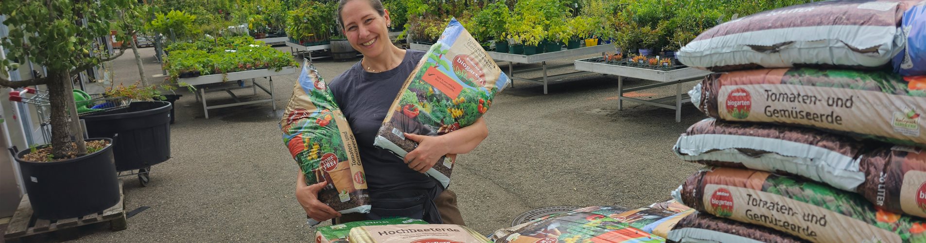 frau hält zwei erdesäcke in der hand und lacht in die kamera frau hält zwei erdesäcke in der hand und lacht in die kamera